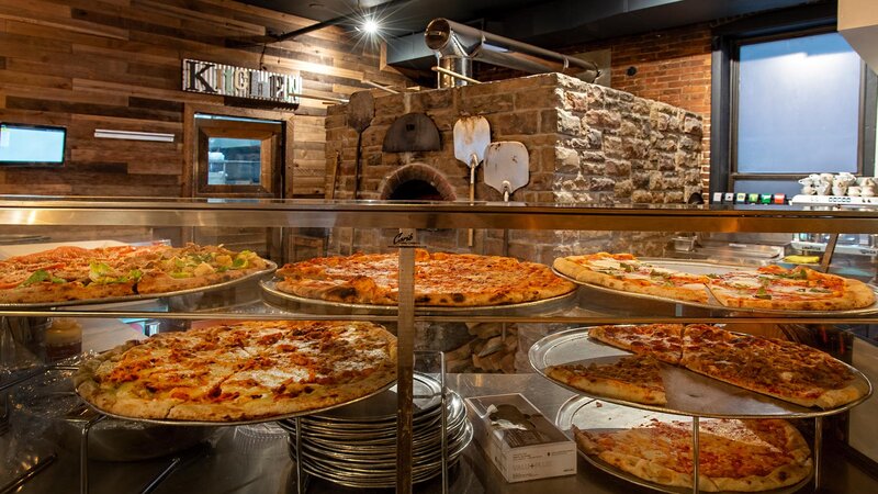 Many pizza pies on counter