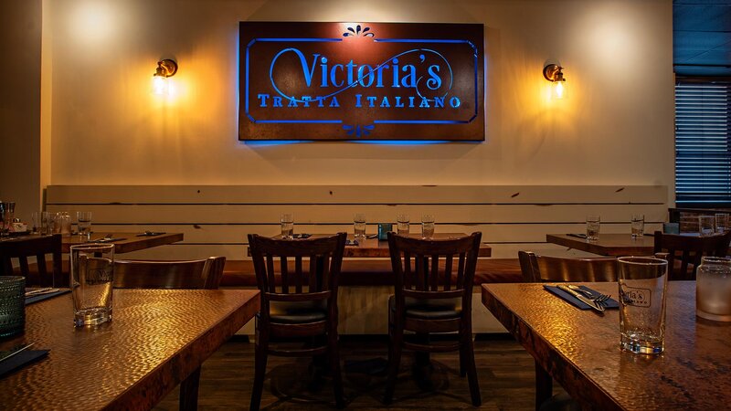Dining room tables with view of Victoria's Tratta Italiano sign on the wall