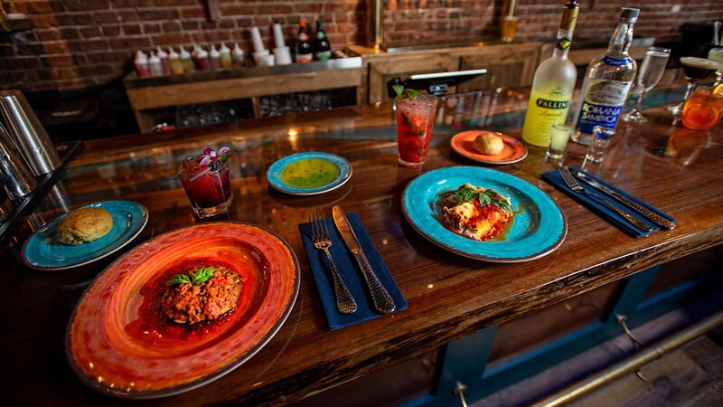 Lasagna entree with sausage portobello mushroom appetizer on the bar with several drinks